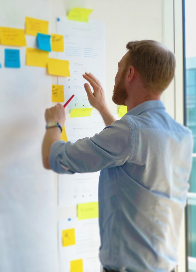 Marketing agency client writing on sticky notes stuck to a wall during a planning workshop