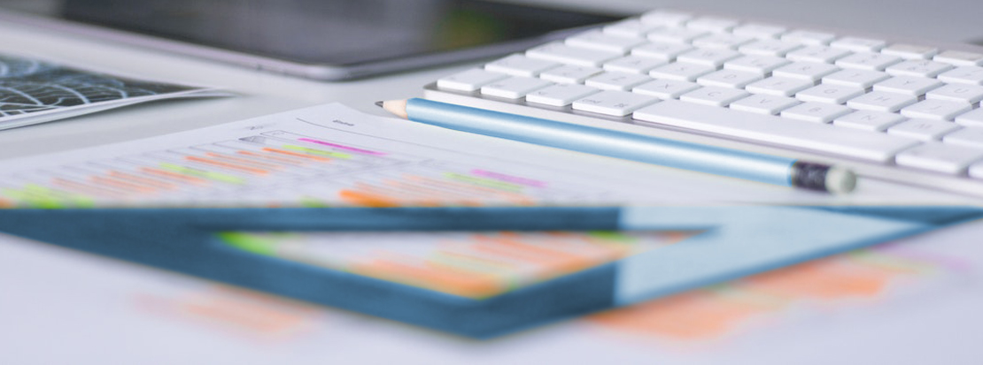 Close up of a blue pencil and protractor on a desk inside a marketing agency office